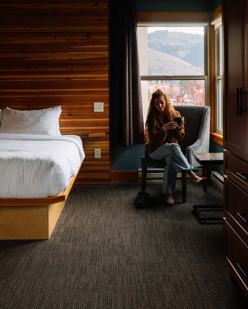 barefoot woman sitting in a hotel room drinking coffee